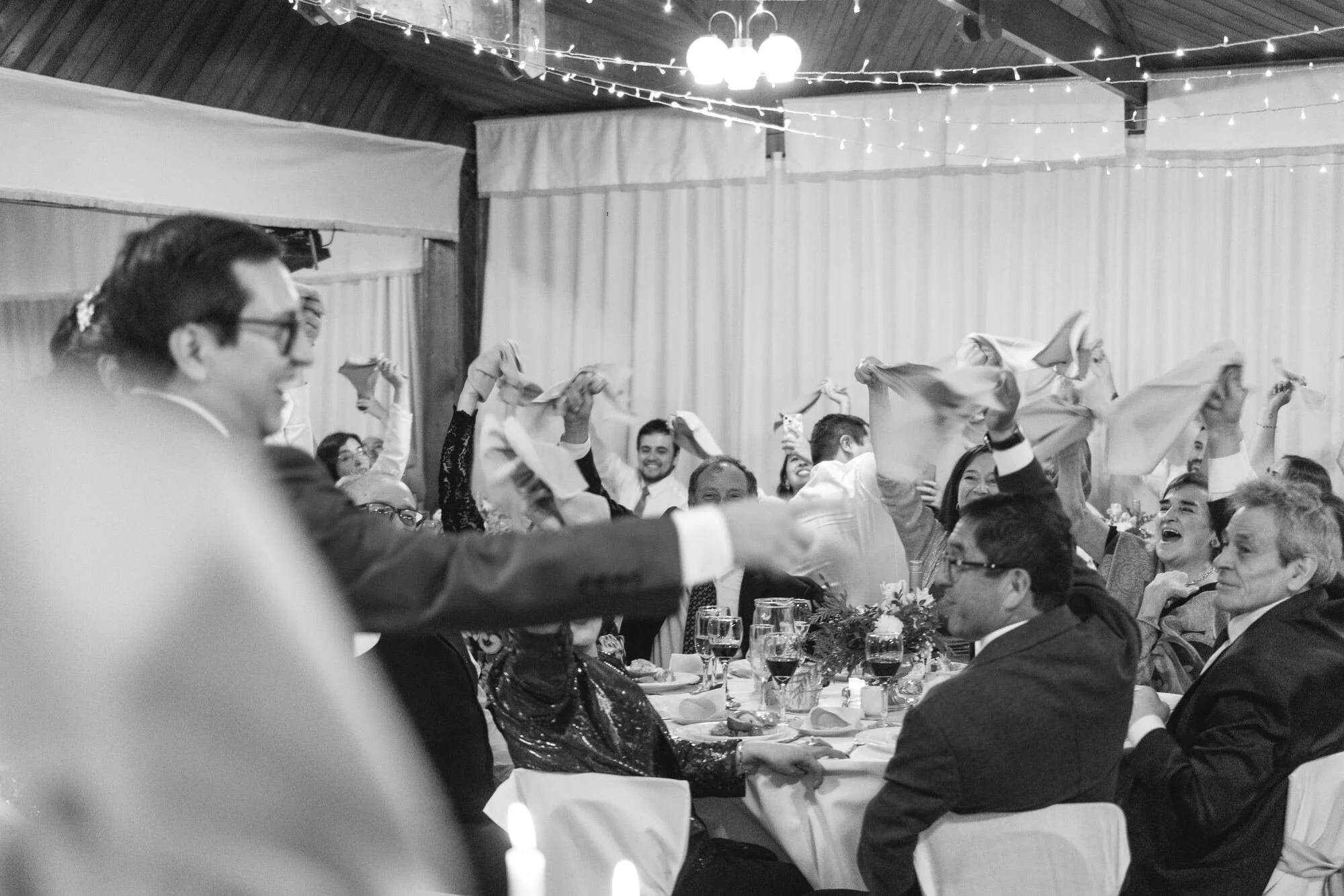 Los invitados brindando con servilletas en alto, en blanco y negro, Castro, Chiloé	