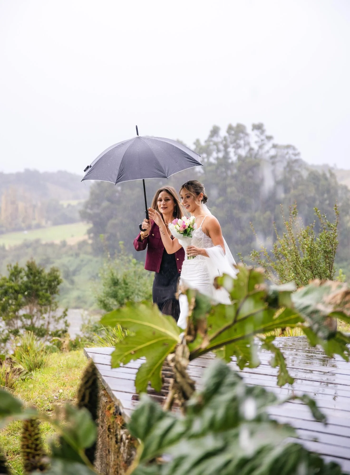 La novia camina bajo la lluvia protegida por un paraguas en Castro, Chiloé