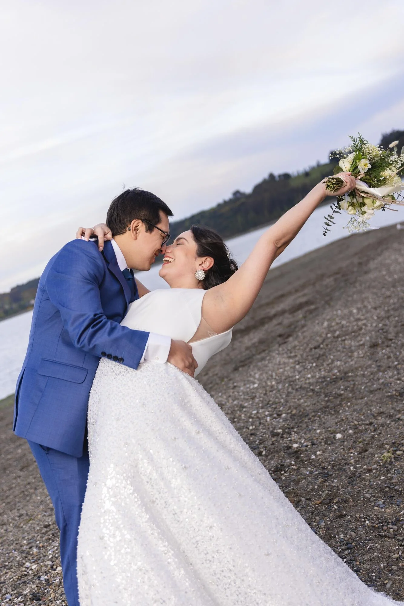 Beso de los novios en la playa mientras la novia levanta su ramo, Castro, Chiloé	