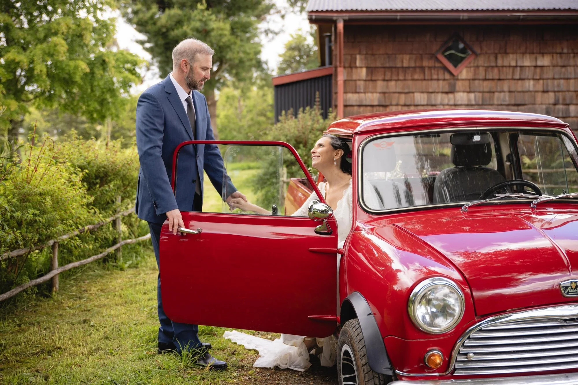 El novio abre la puerta del auto clásico rojo a la novia, Castro, Chiloé	