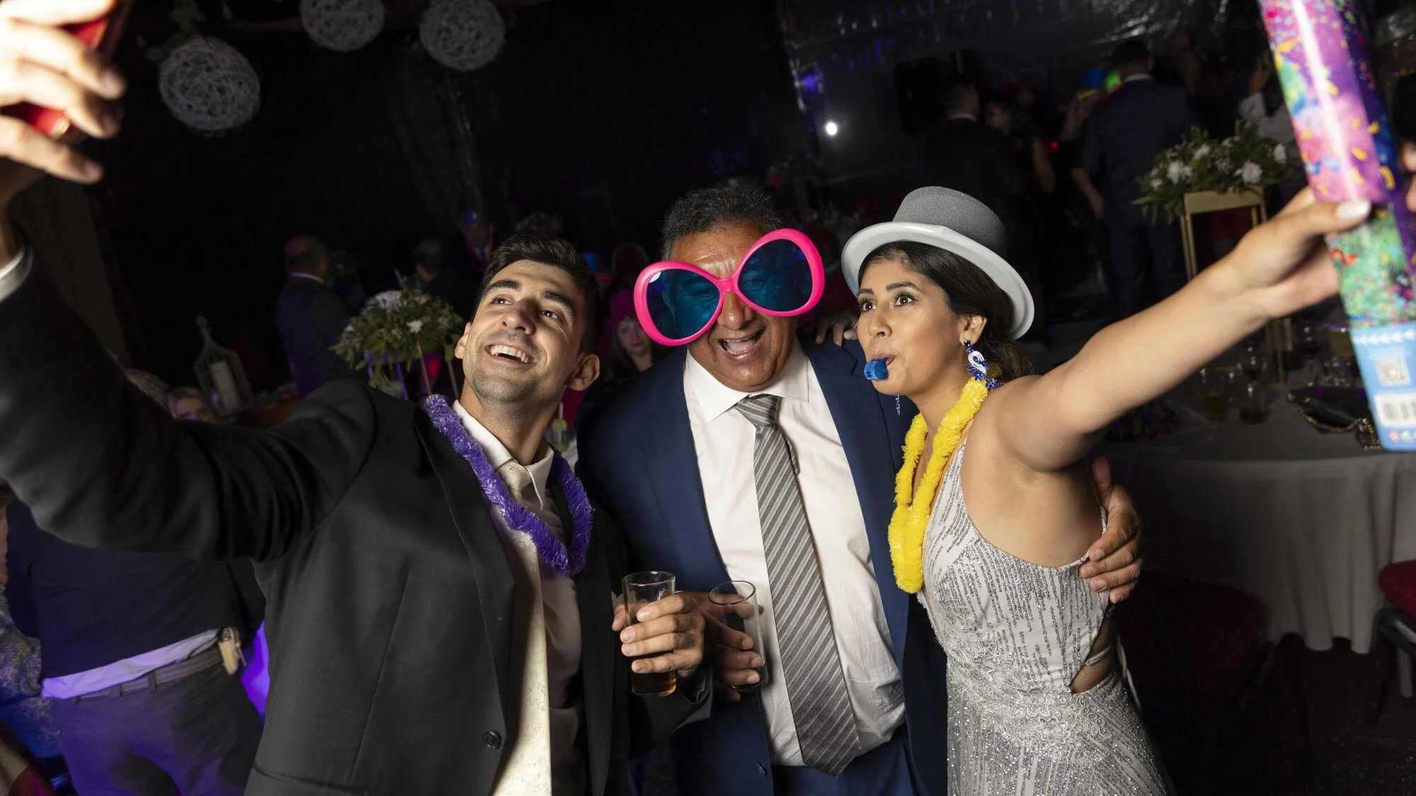 Invitados celebrando con lentes y sombreros en la fiesta de matrimonio en Quilquico, Chiloé
