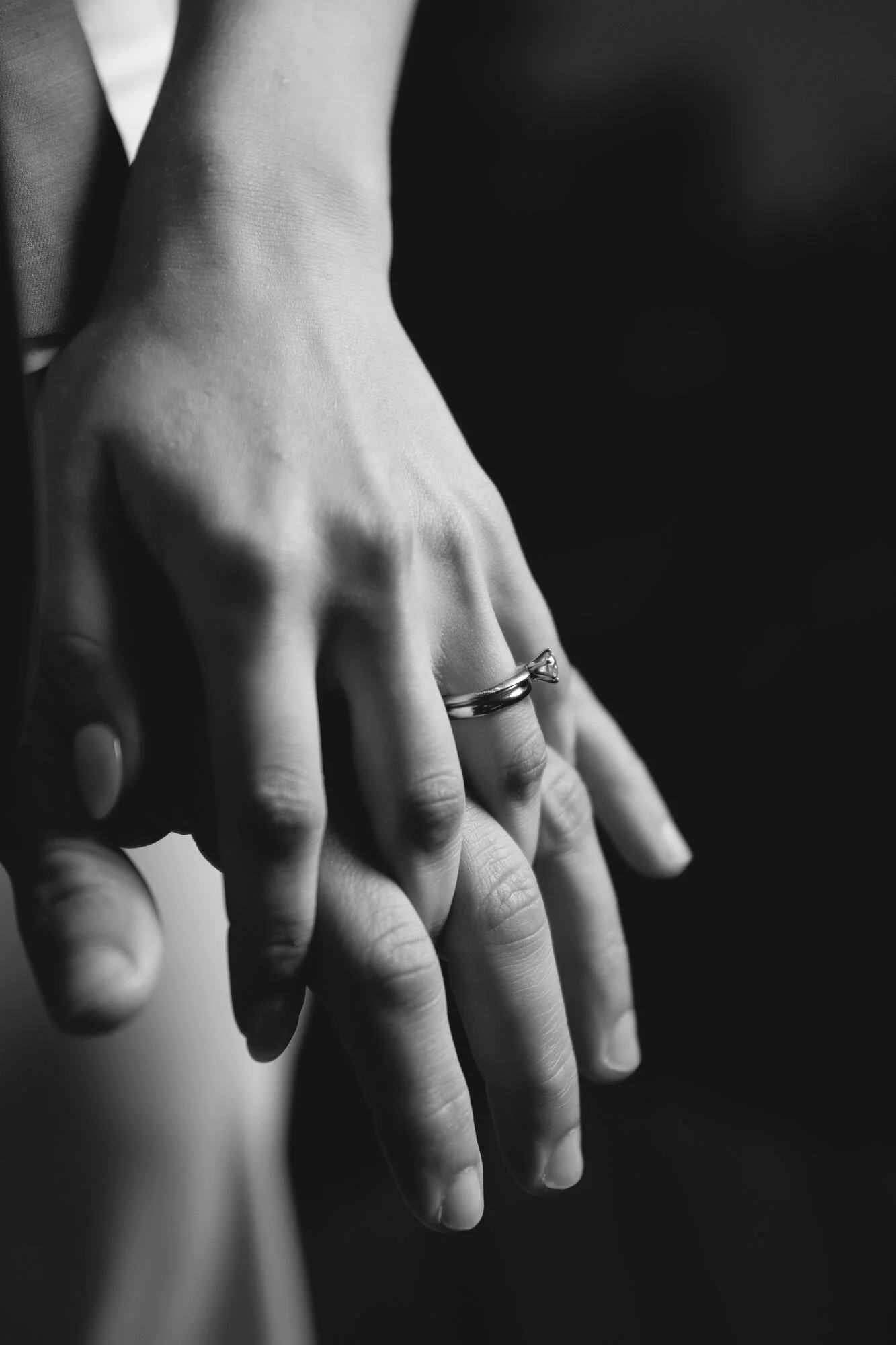 Manos entrelazadas de los novios con sus argollas, en blanco y negro, Refugia