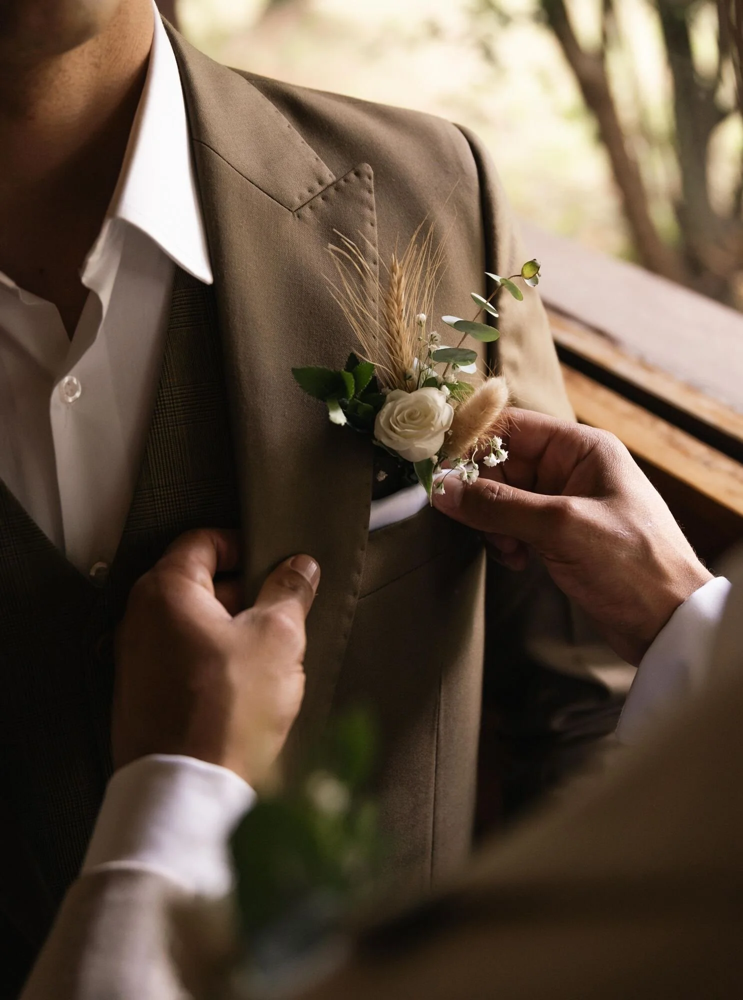 Detalle del boutonniere con rosa blanca colocado en el traje del novio durante los preparativos en Ancud