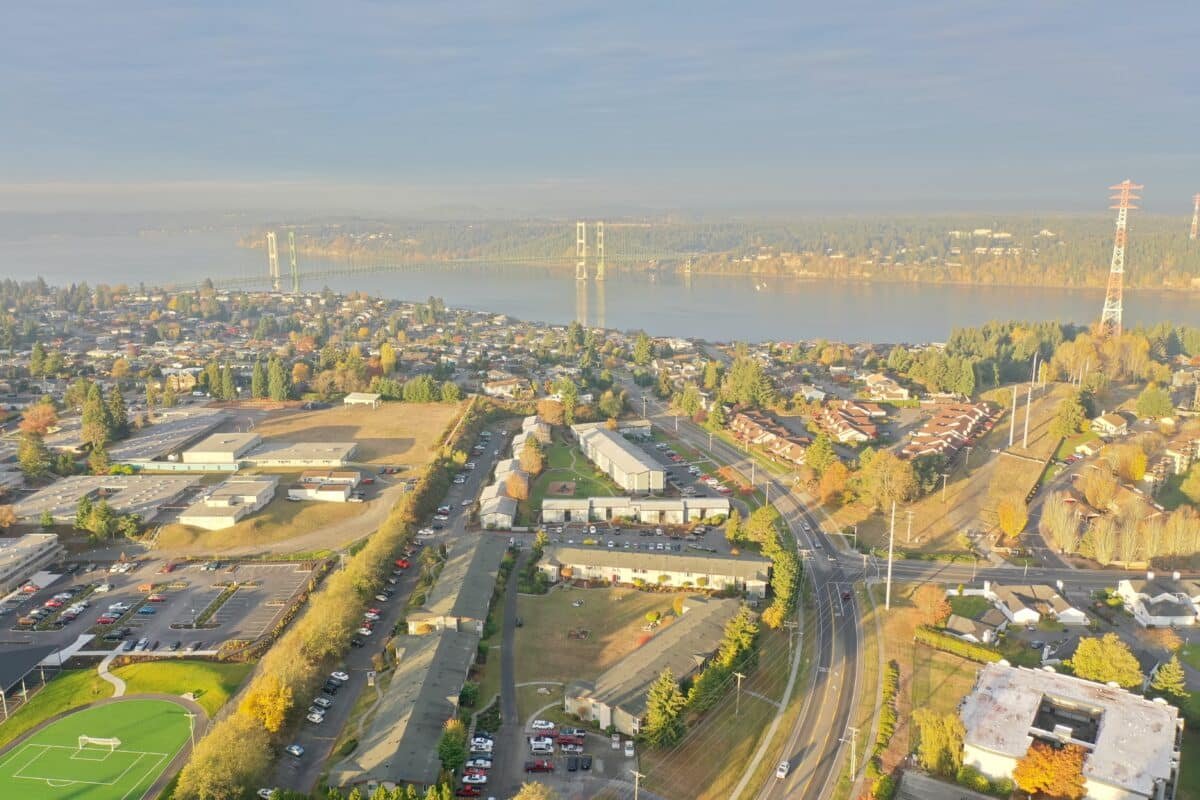 Aerial view of a cityscape with a river, bridges, residential and commercial buildings, trees, and roads, taken during daytime.