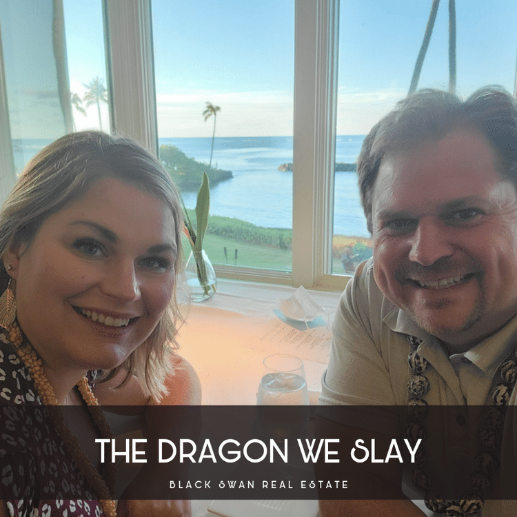 Two people smiling at a table with a view of the ocean, palm trees, and bright sky outside the window.