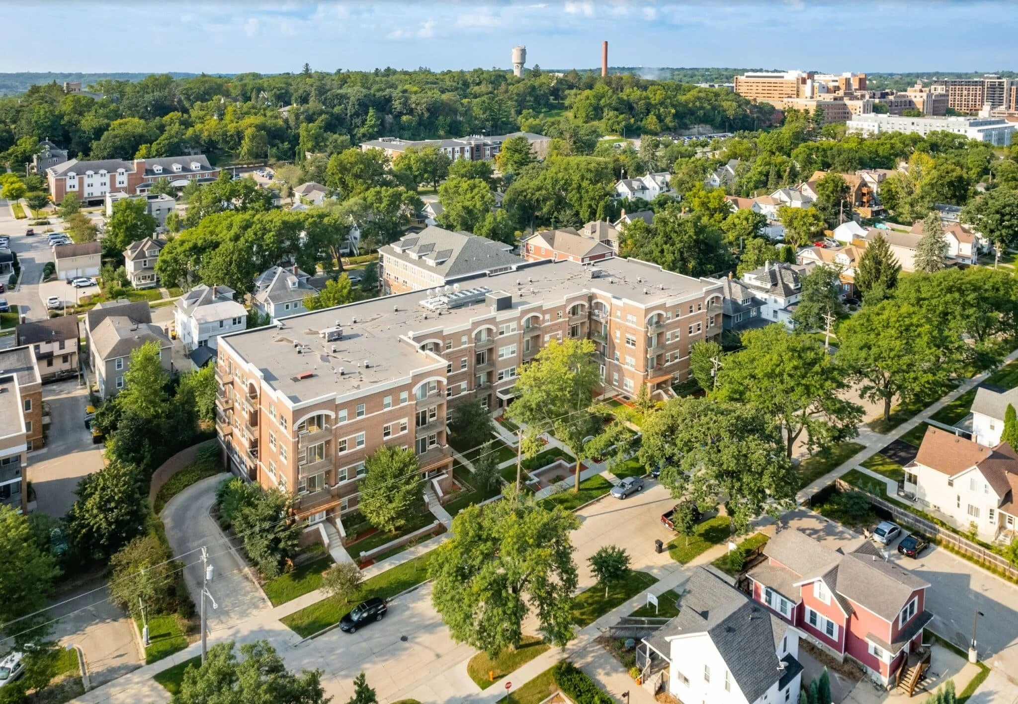 Aerial view of a residential neighborhood with houses, apartment buildings, and trees on a sunny day.