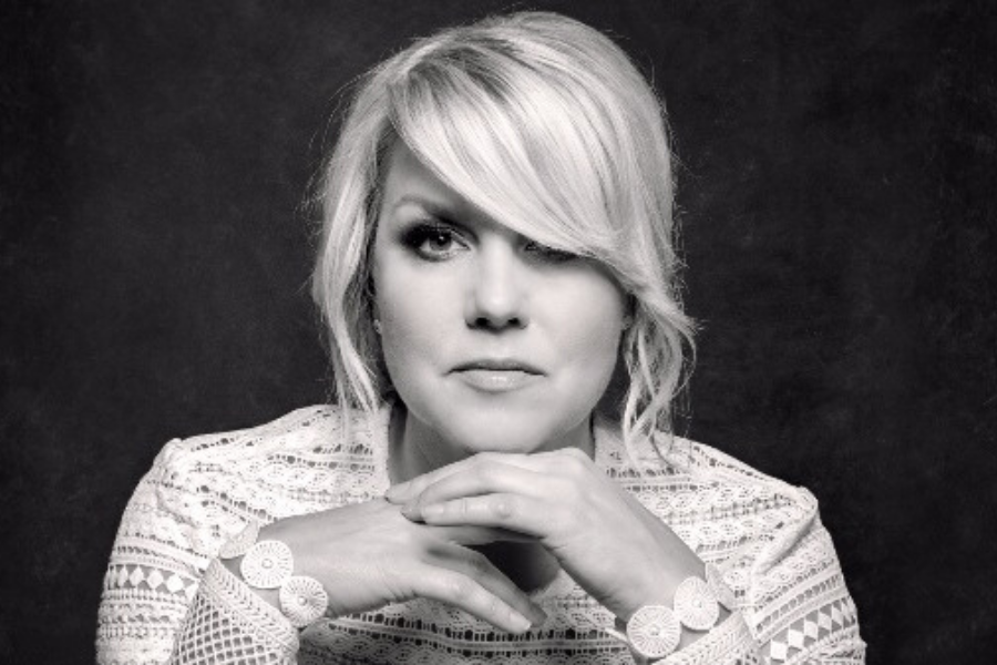 Black and white portrait of Nichole Nordeman, award-winning Christian singer-songwriter and author, with shoulder-length blonde hair, wearing a lace top and a bracelet. She rests her chin on her hands, looking directly at the camera.