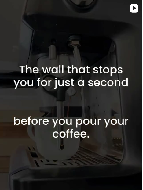 Close-up of a coffee machine's interior with a white coffee mug underneath, with overlaid text saying 'The wall that stops you for just a second before you pour your coffee.'