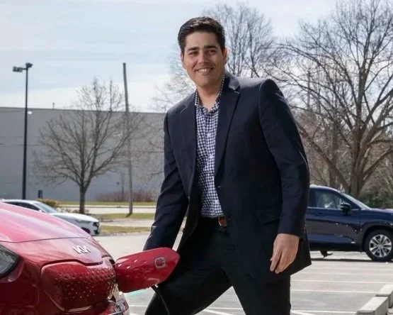 Young man in navy blazer next to red car
Alex Banat, host of The Climate Layer podcast, photographed outdoors.
