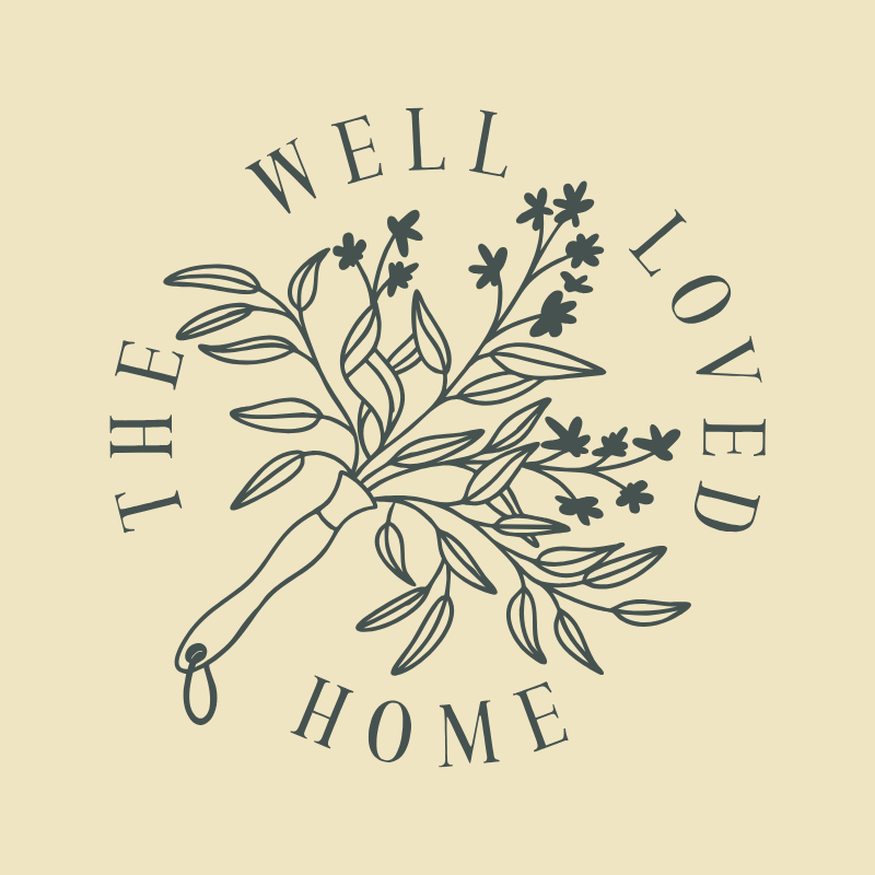 A decorative illustration of a pruning shear cutting a bouquet of flowers and leaves, with the words "The Well Loved Home" arched around the image.