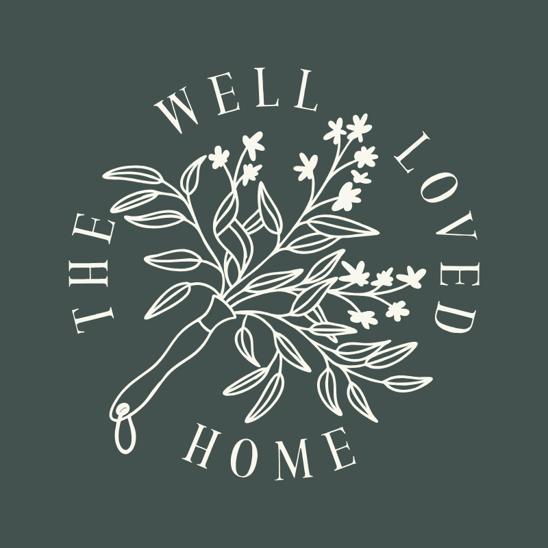 A minimalist illustration of a pair of garden shears with flowers and leaves, surrounded by the words 'The Well Loved Home' in a circular order.