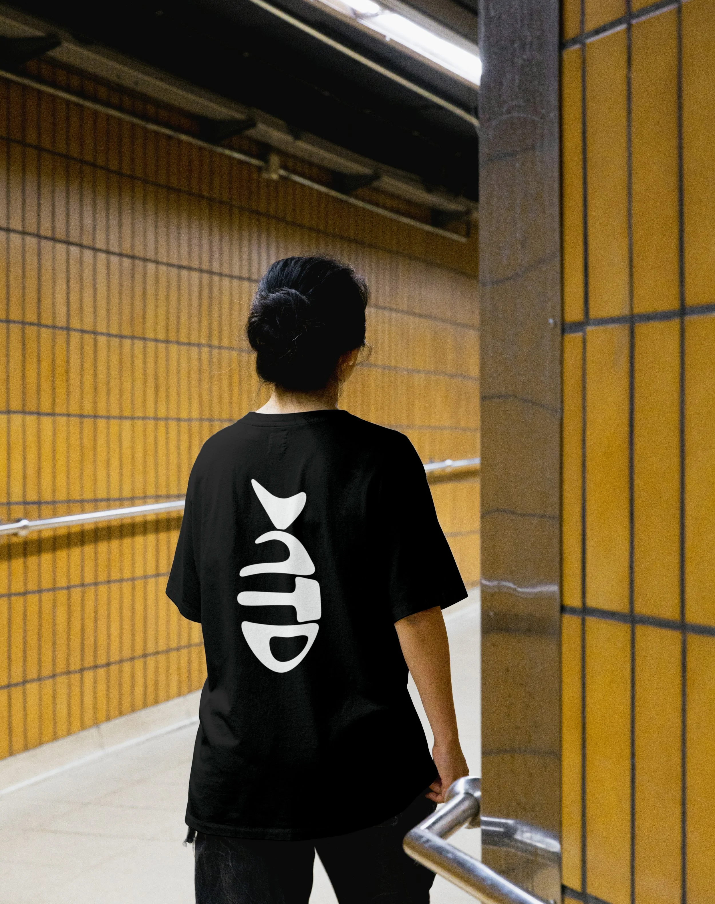 Not That Deep black t-shirt with 3D fish logo, woman walking away