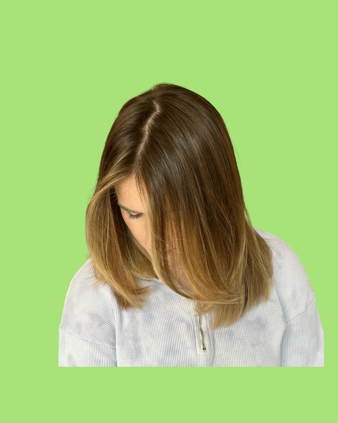 A woman with shoulder-length brown hair looking down, wearing a white zip-up top, against a lime green background.