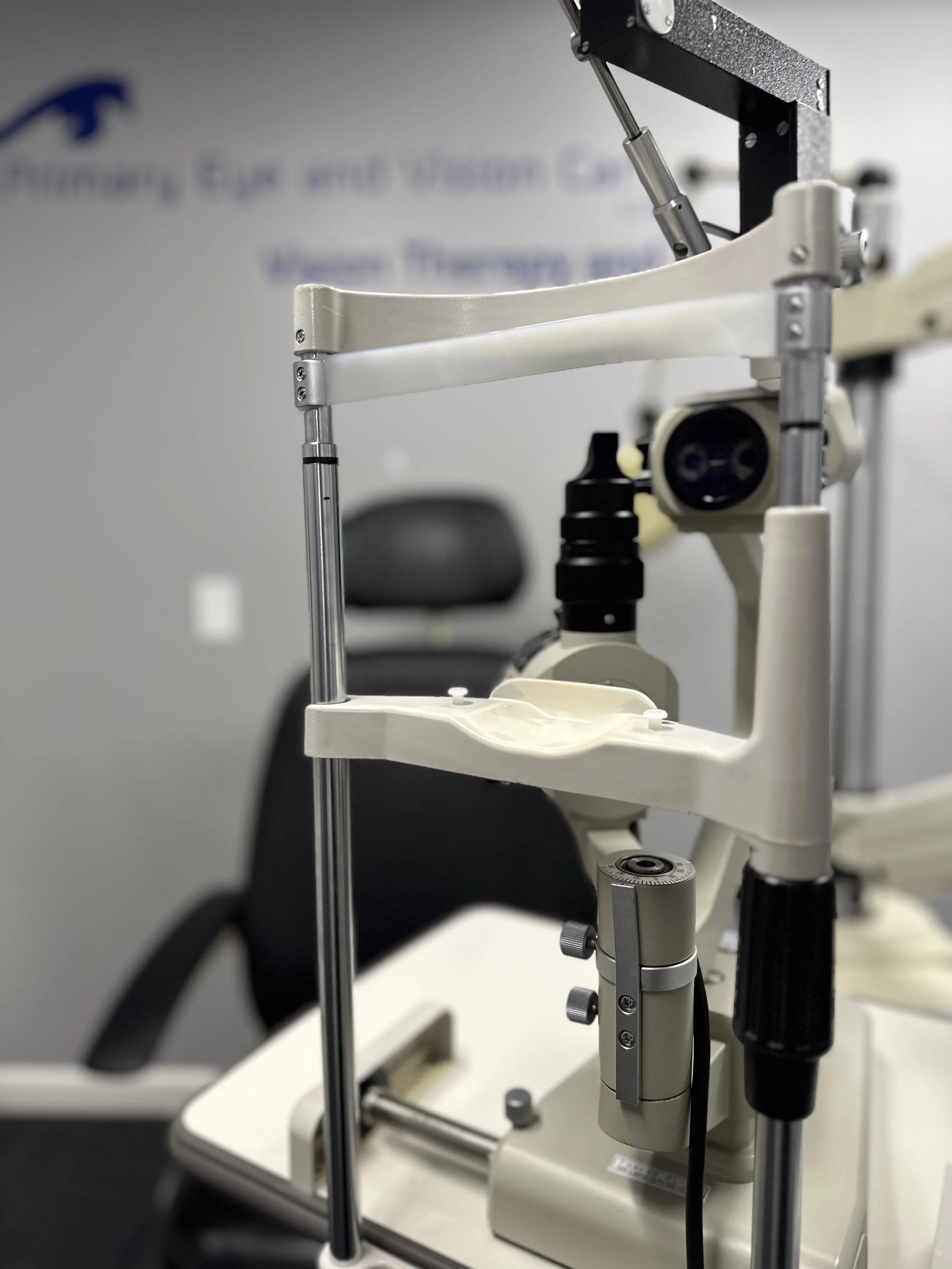 Close-up of a medical microscope with adjustable arms and focus knobs in a laboratory or medical setting.