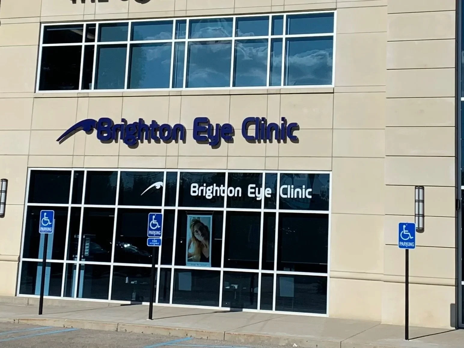 Exterior of Brighton Eye Clinic with blue signage, large windows, and accessible parking signs near the entrance.