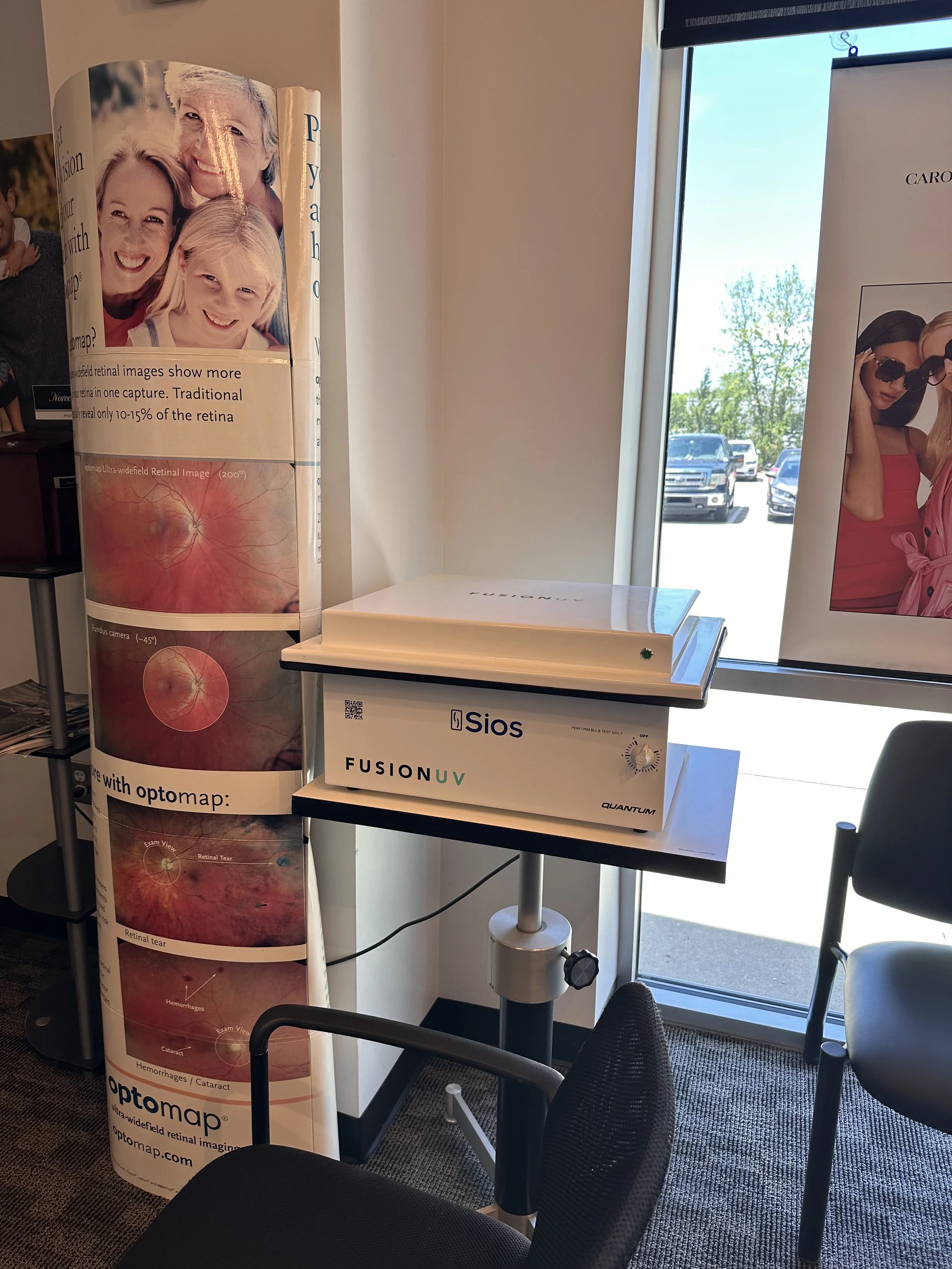 Medical display stand with informational posters about eye health, including retinal images, in a room with chairs and a window.