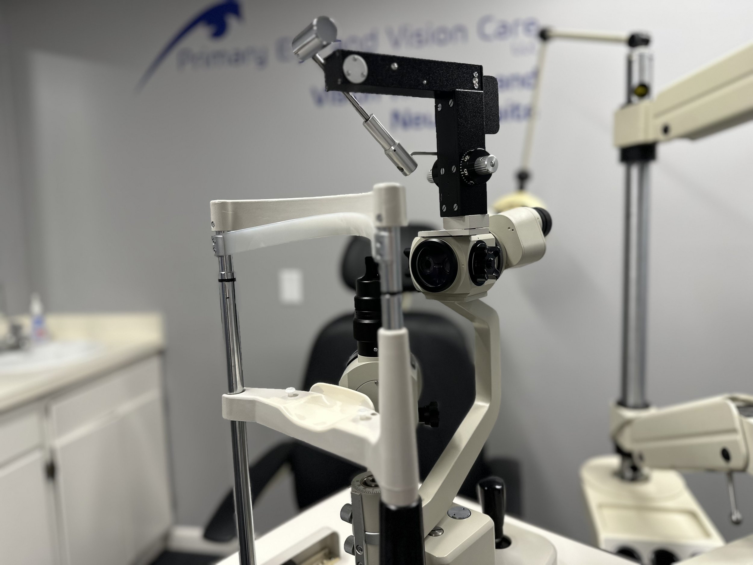 A microscope in a laboratory with a white wall in the background.