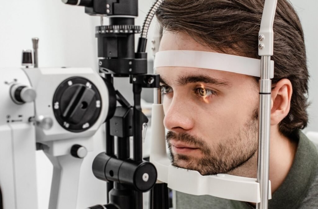 A man undergoing an eye examination using a slit lamp at an optometrist's office.