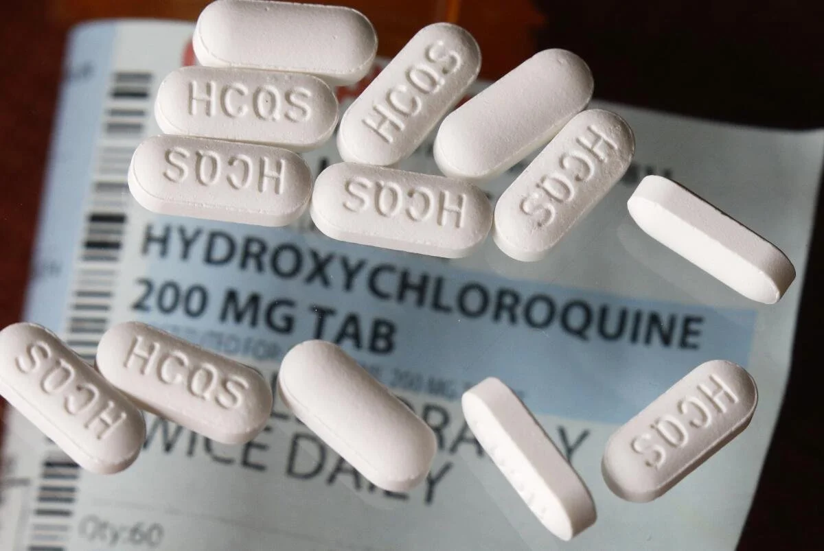 White tablets labeled H C S for hydroxychloroquine on a medication box that reads 'HYDROXYCHLOROQUINE 200 MG TAB'.