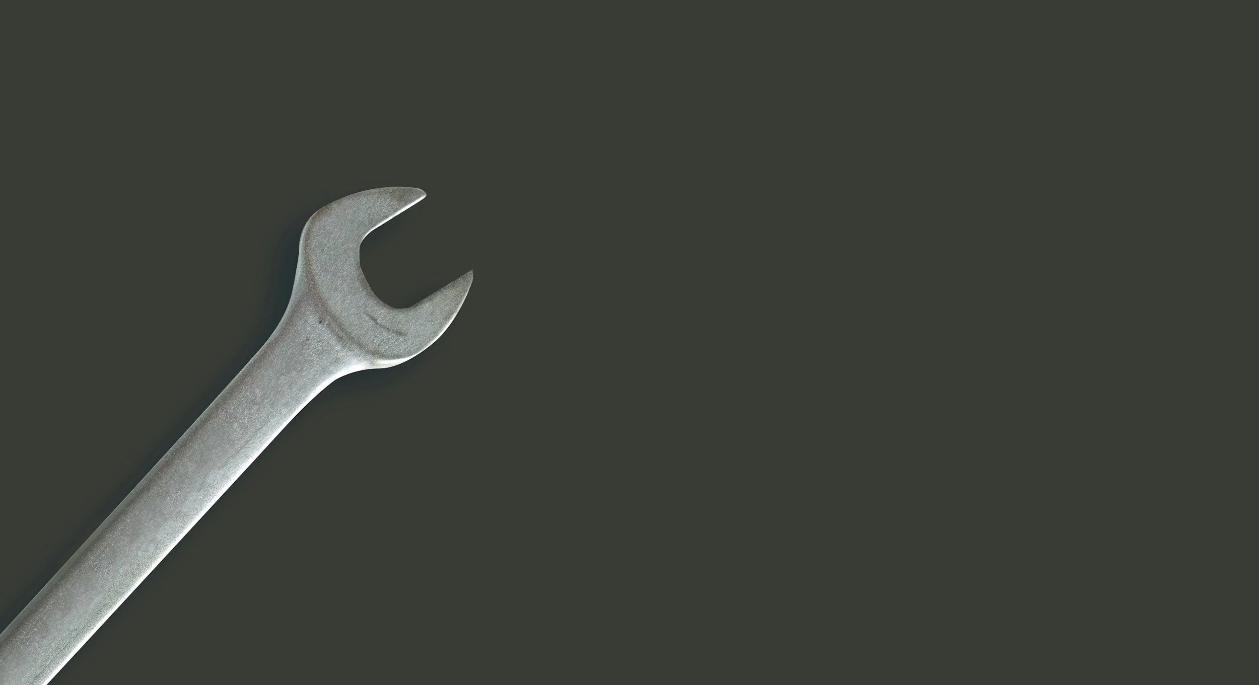 A silver open-end wrench on a dark background.