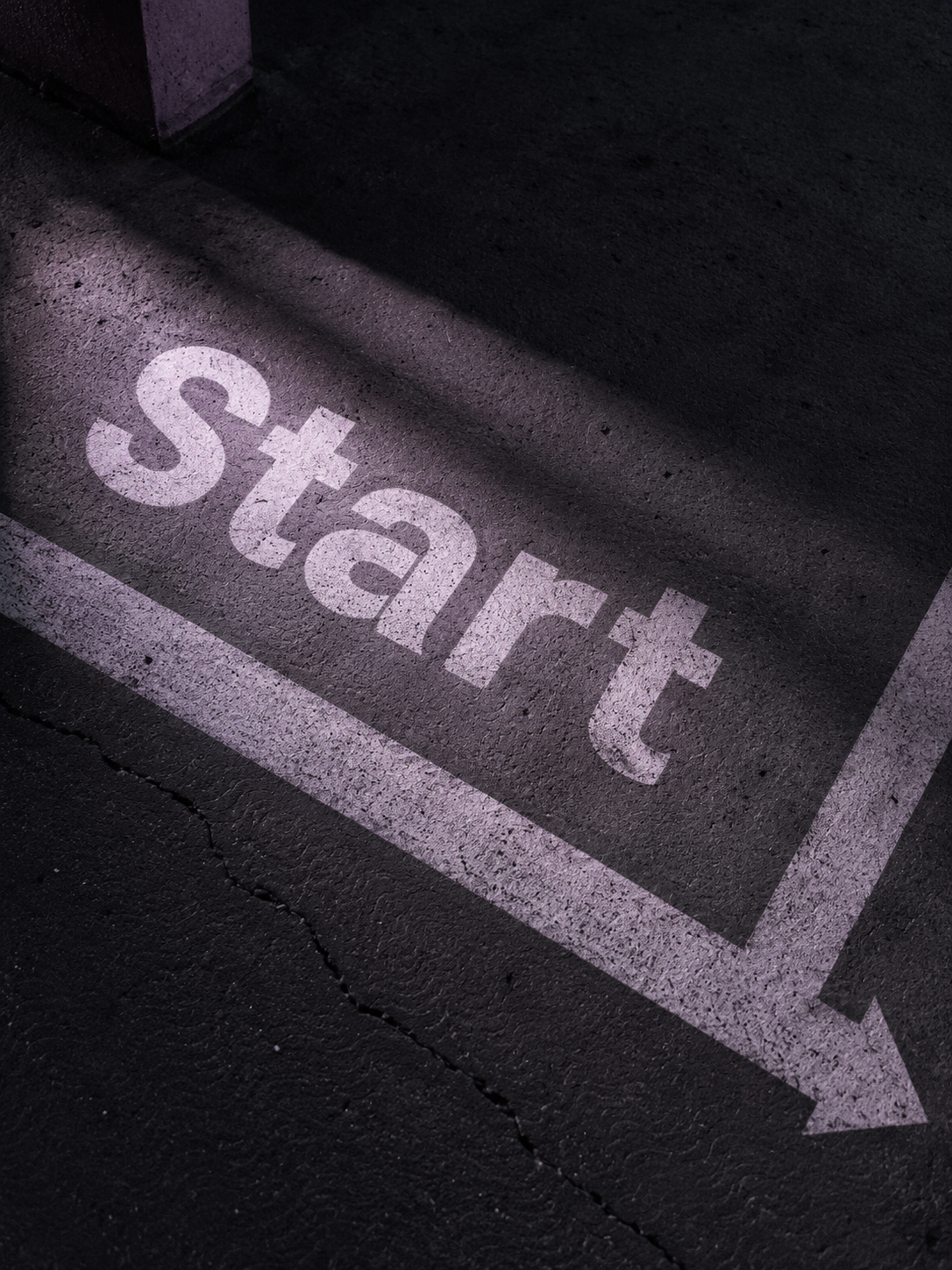 A painted arrow with the word 'Start' on a dark asphalt surface.