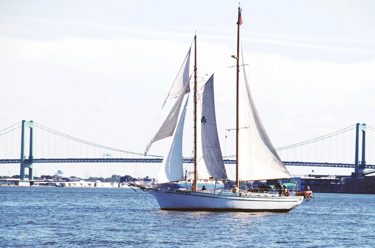 A sailboat on the water with a bridge in the background.