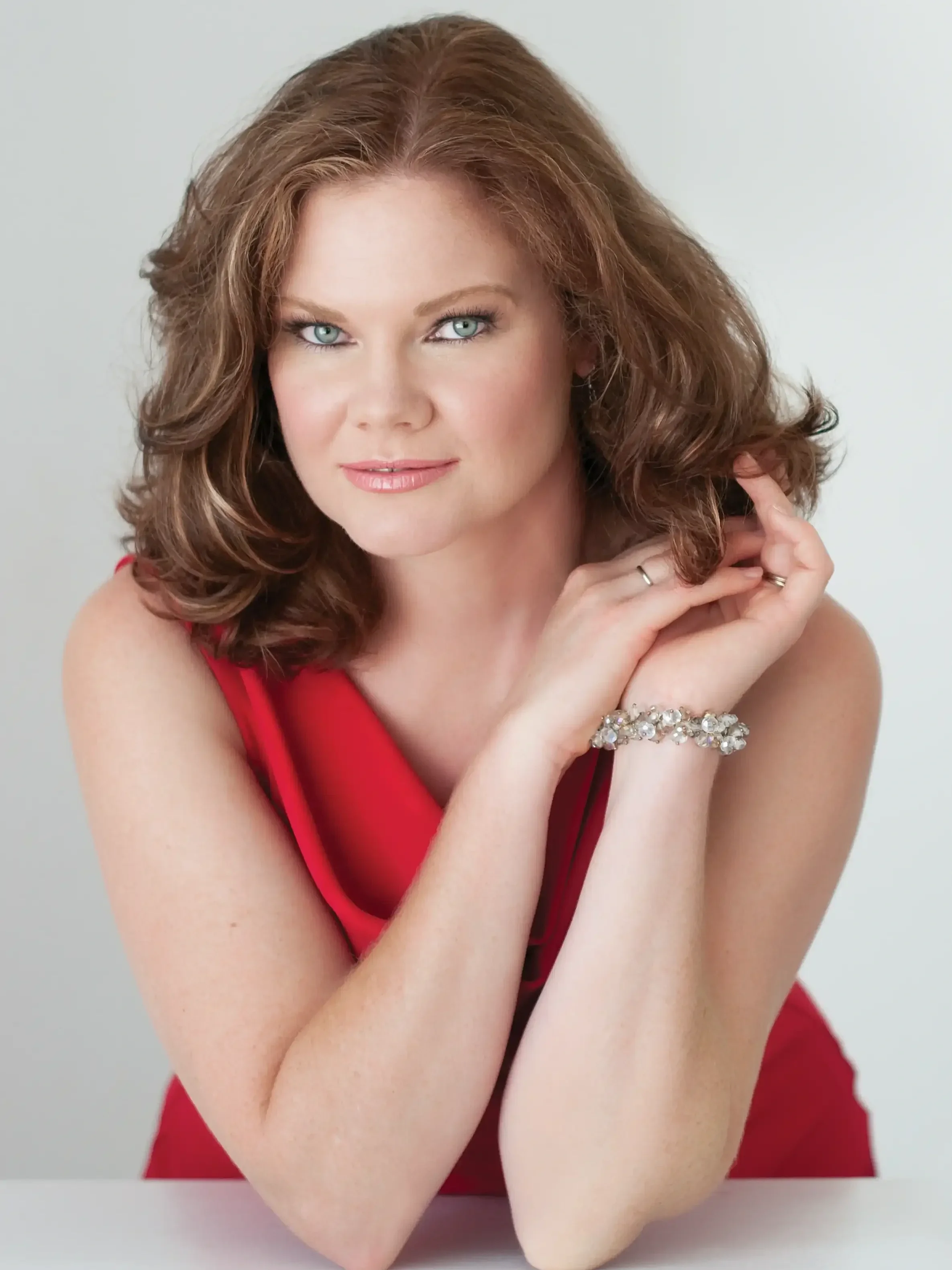headshot of auburn haired woman wearing a red dress.