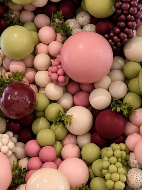 Colorful decorative balls in pink, green, white, and burgundy with some greenery.