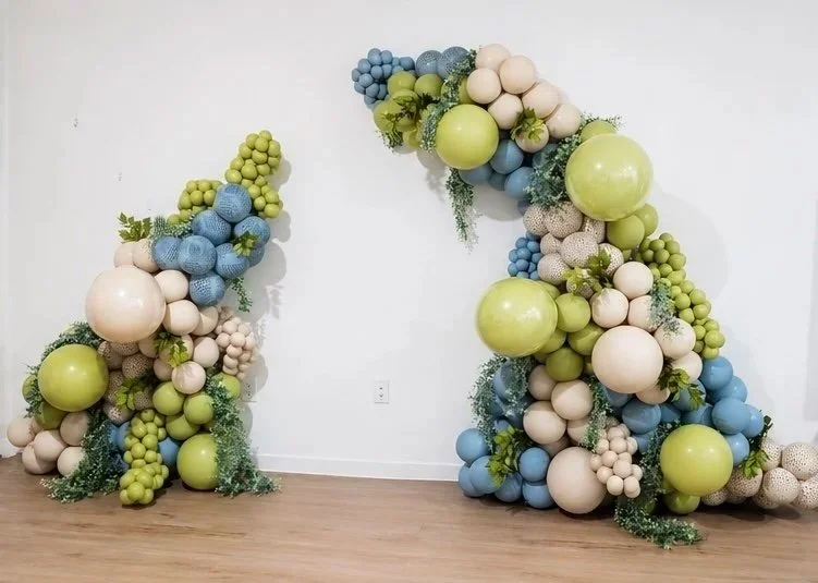 Decorative arch made of green, blue, and white balloons arranged in a floral and organic pattern.