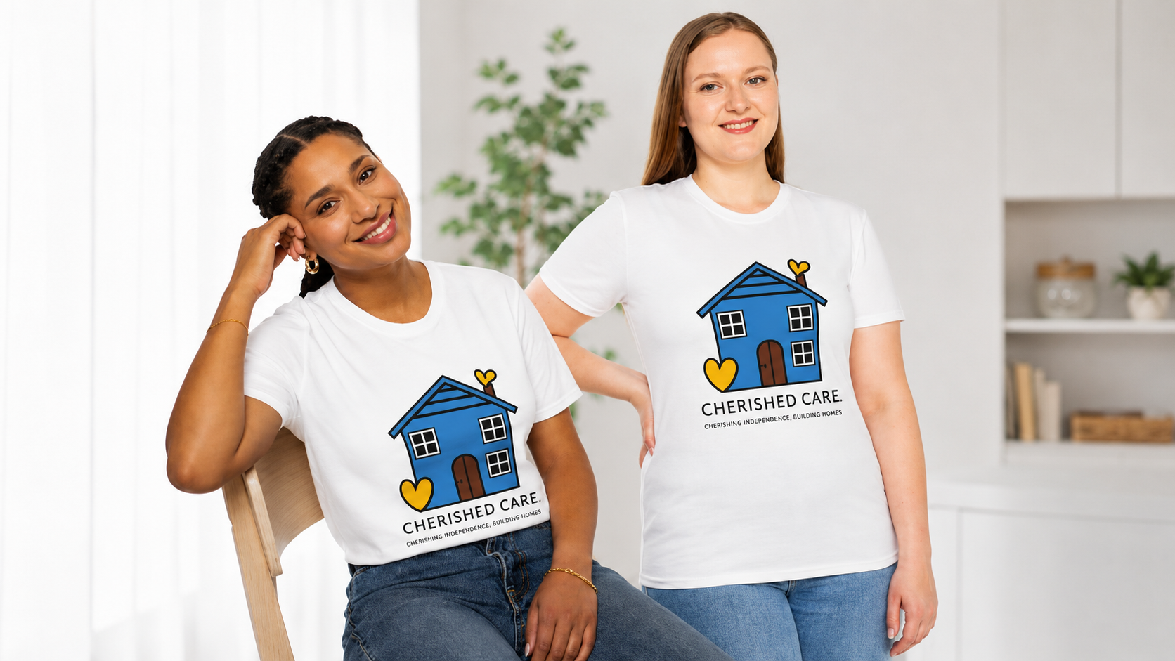 Two women wearing white t-shirts with a blue house logo and the words 'Cherished Care.' They are in a bright room with a plant in the background, smiling and posing for the photo.