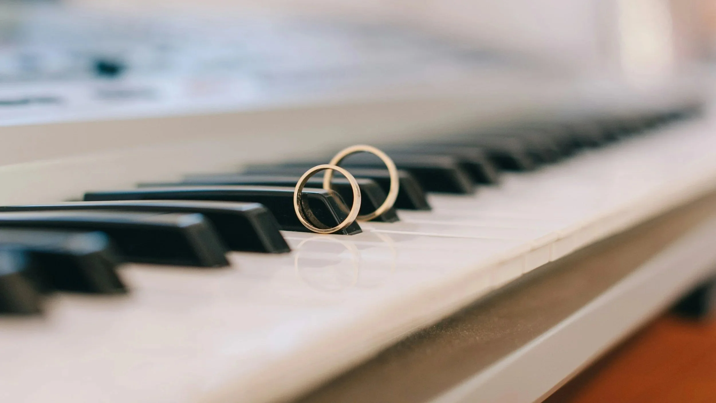 Two gold wedding rings placed on the keyboard of a piano.