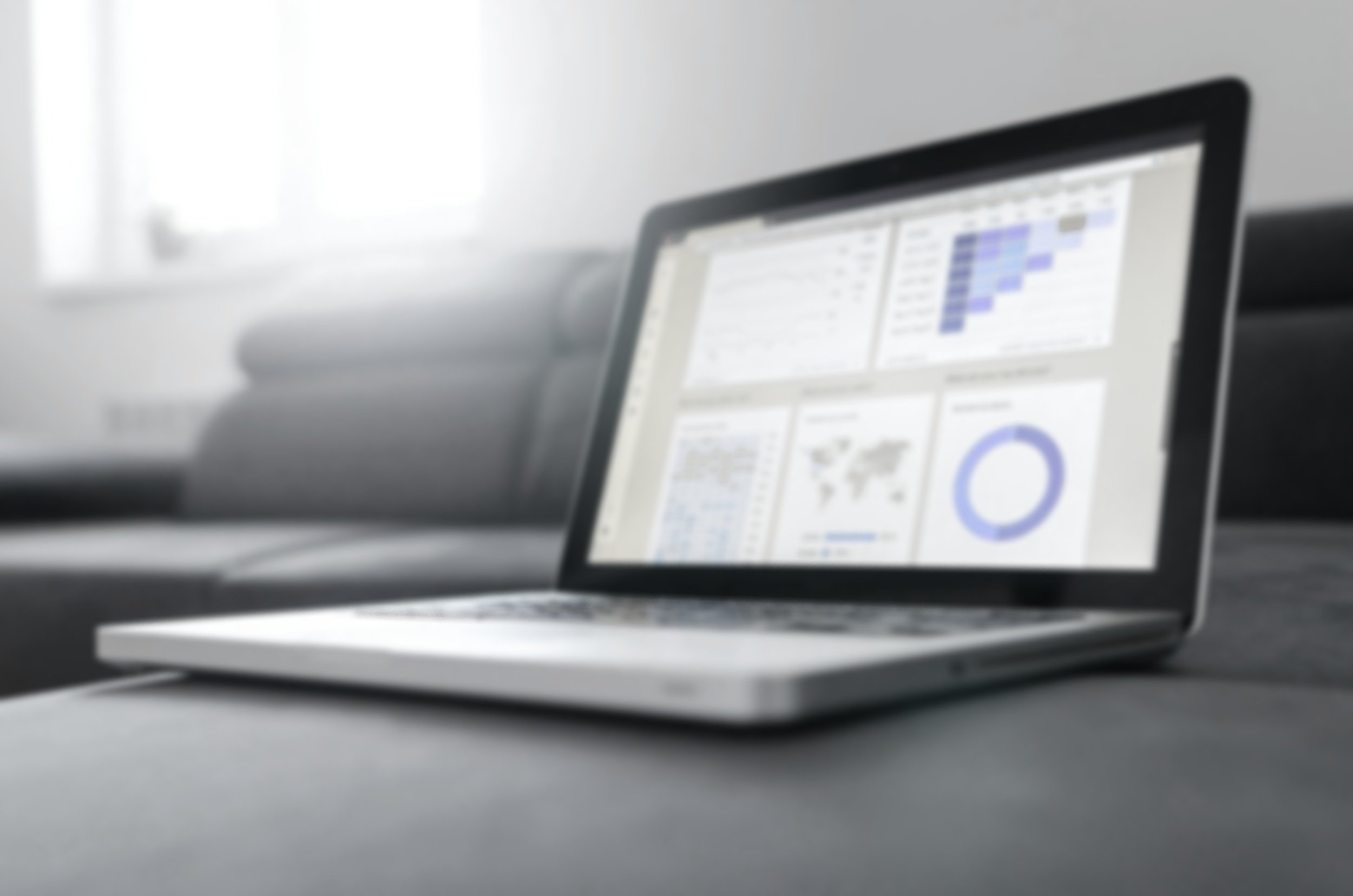 Close-up of a computer monitor displaying dashboards and charts, placed on a desk with a blurred background.