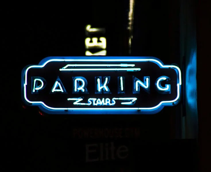 Blue neon sign with the word "PARKING" in the center and an arrow pointing right below it.
