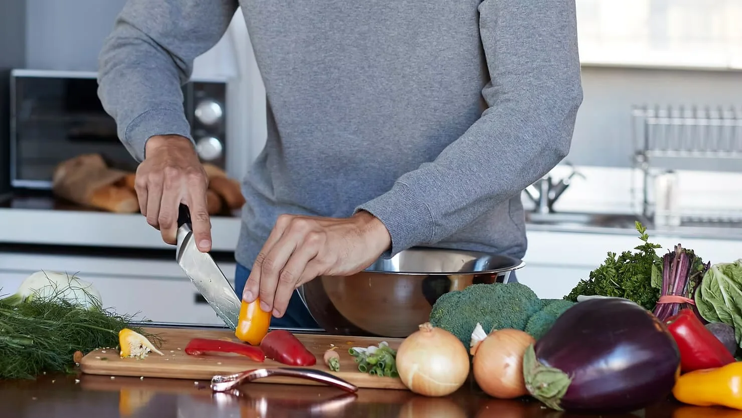 A man cooking a variety of colourful vegetables
