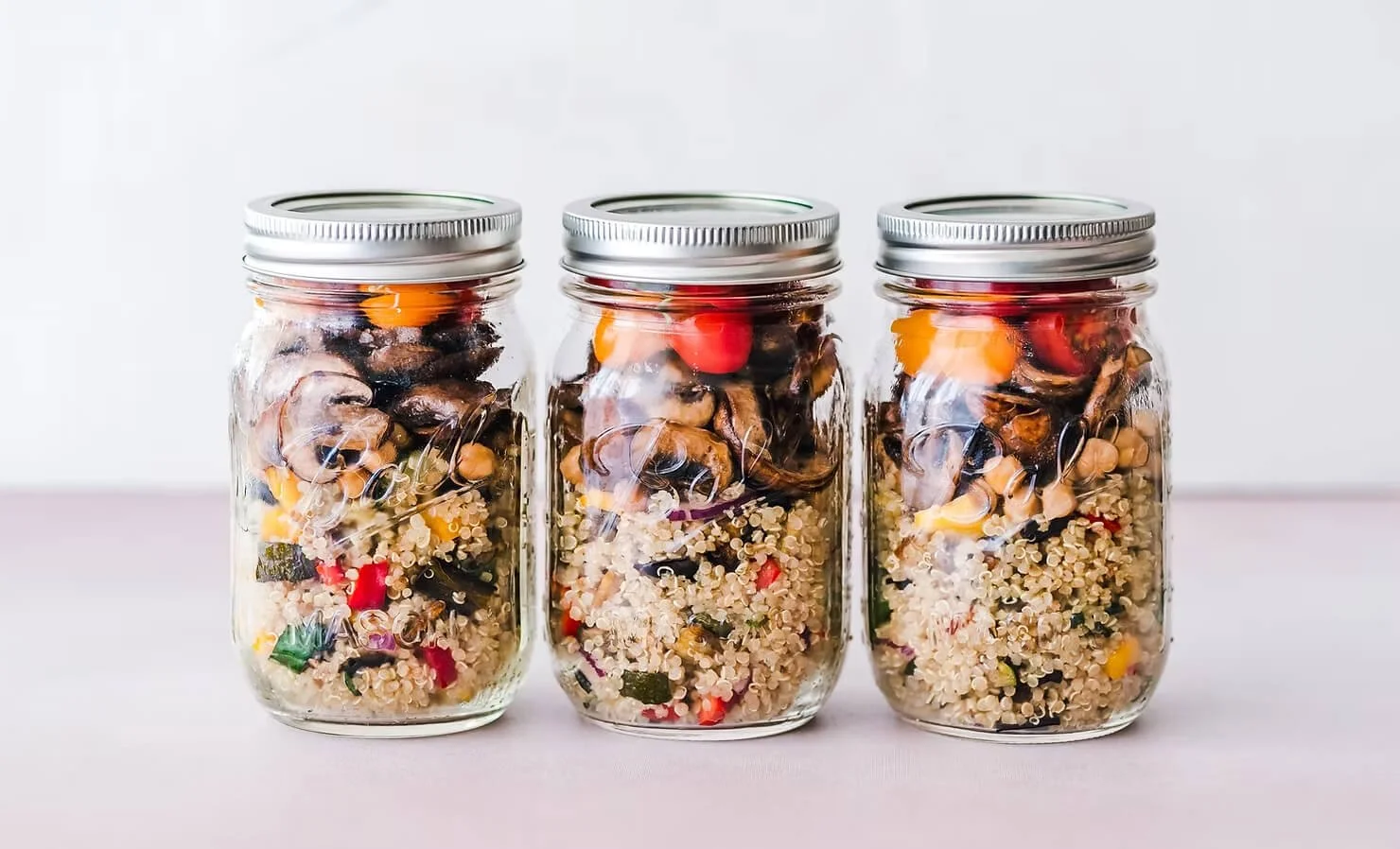 Mason jars filled with high fibre foods including quinoa, vegetables and chickpeas