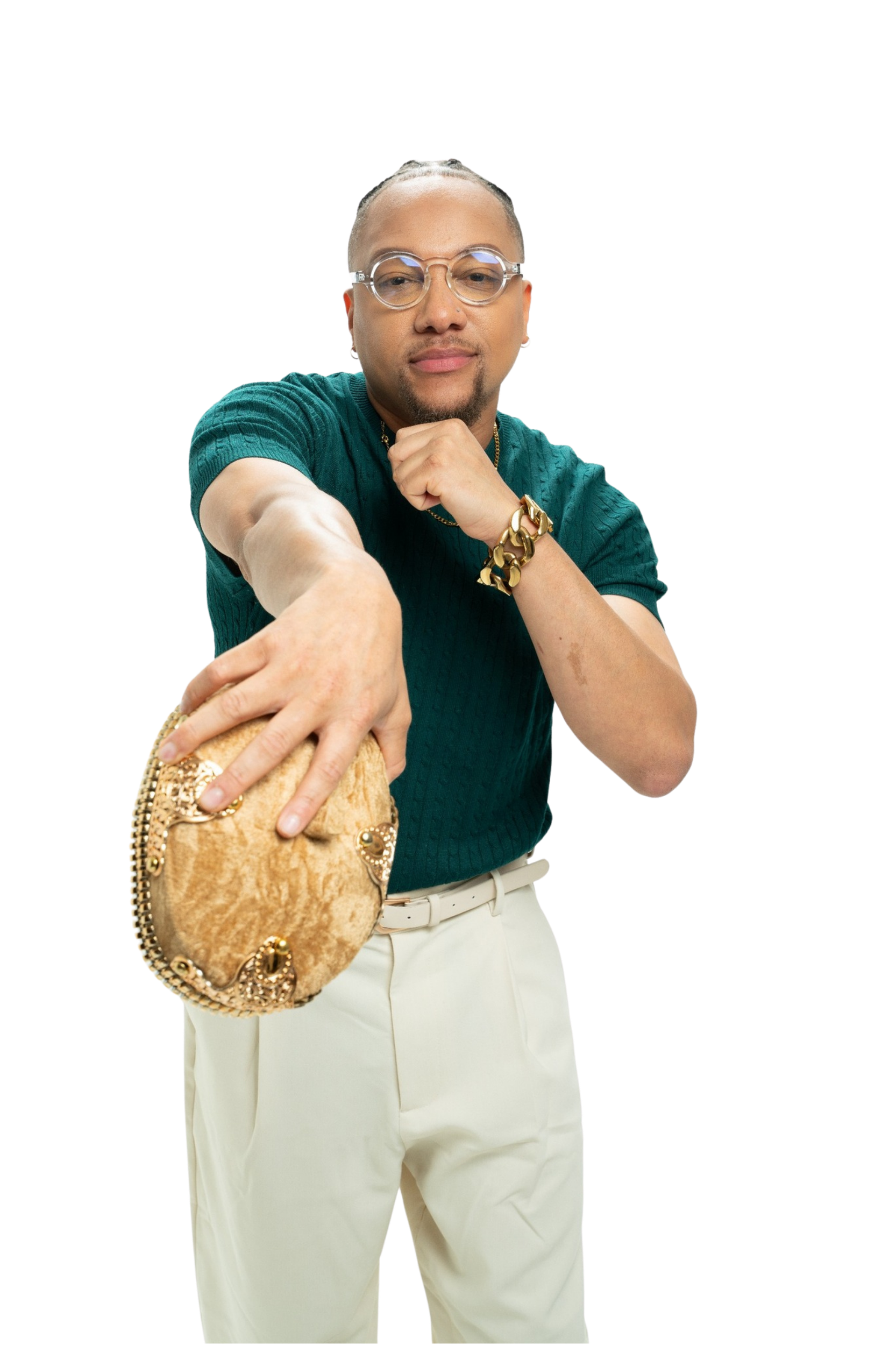 Person wearing glasses, a teal shirt, white pants, and a gold bracelet holding a plush handbag with gold embellishments, standing with one hand on their chin and the other arm extended forward.