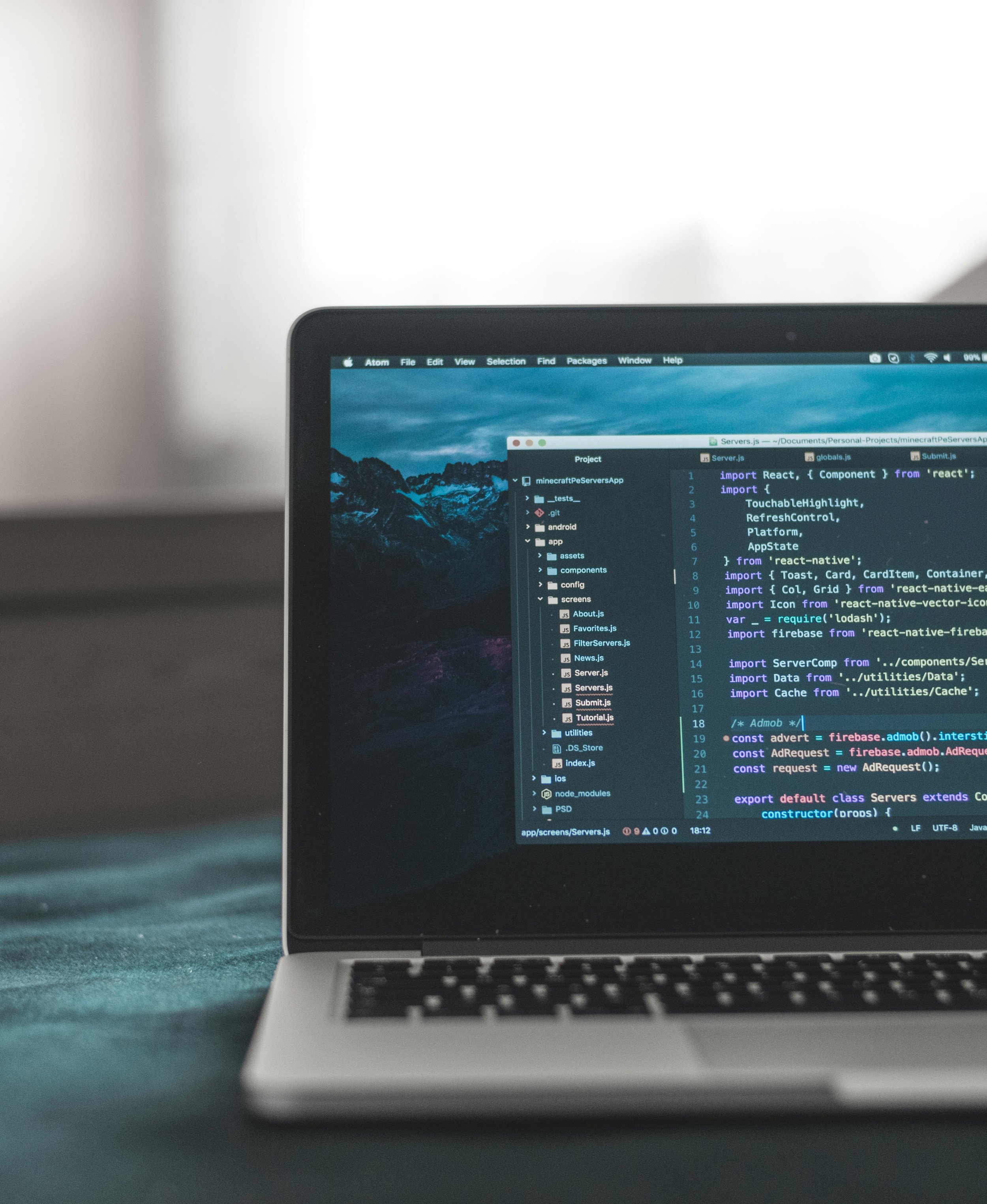 Close-up of a laptop screen displaying a coding project with multiple open files, including 'Server.js', 'globals.js', and 'About.js', on a dark-themed code editor.