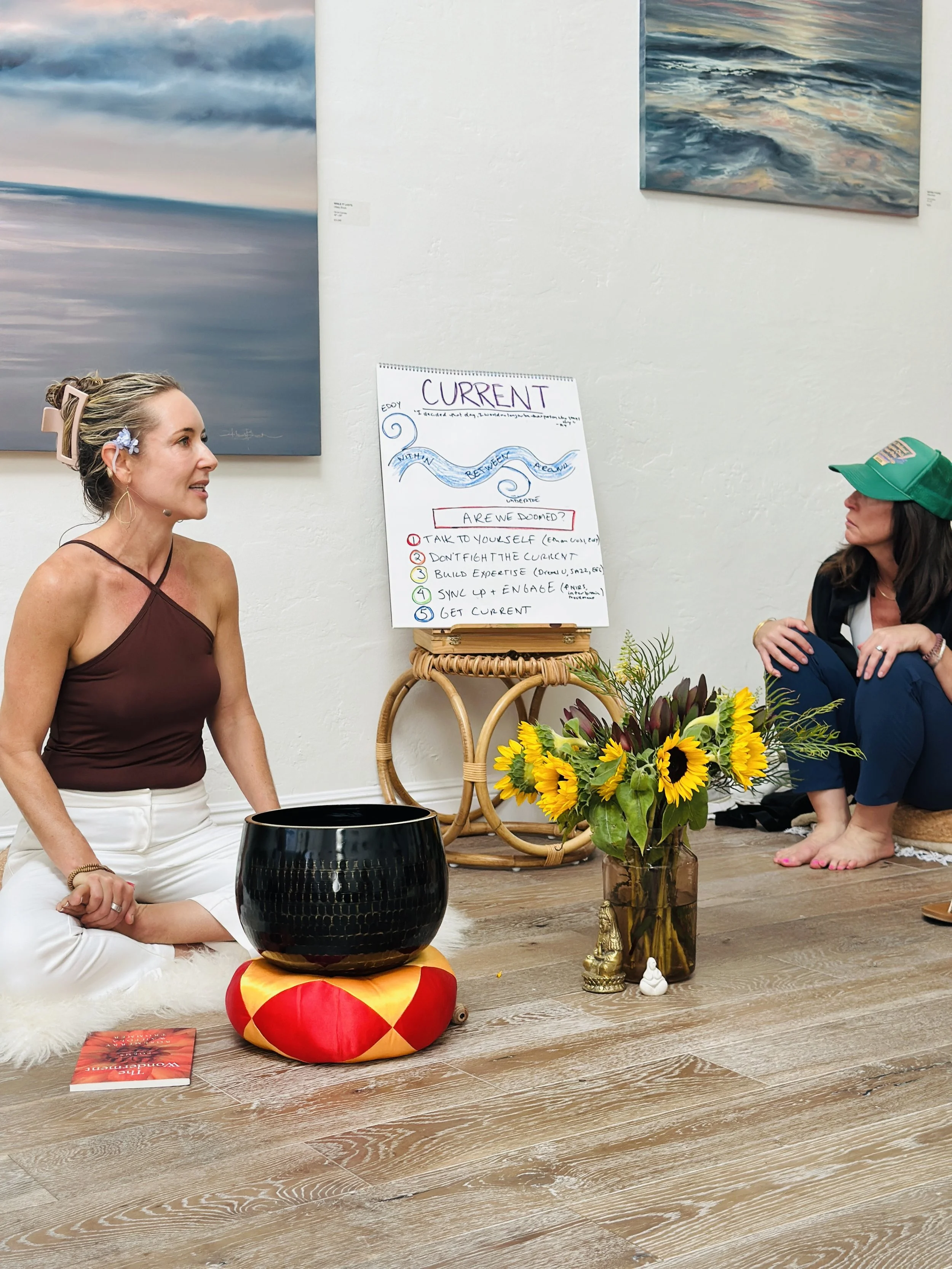 Woman seated on the floor beside a singing bowl and sunflowers, with a CURRENT notepad listing five steps behind her.