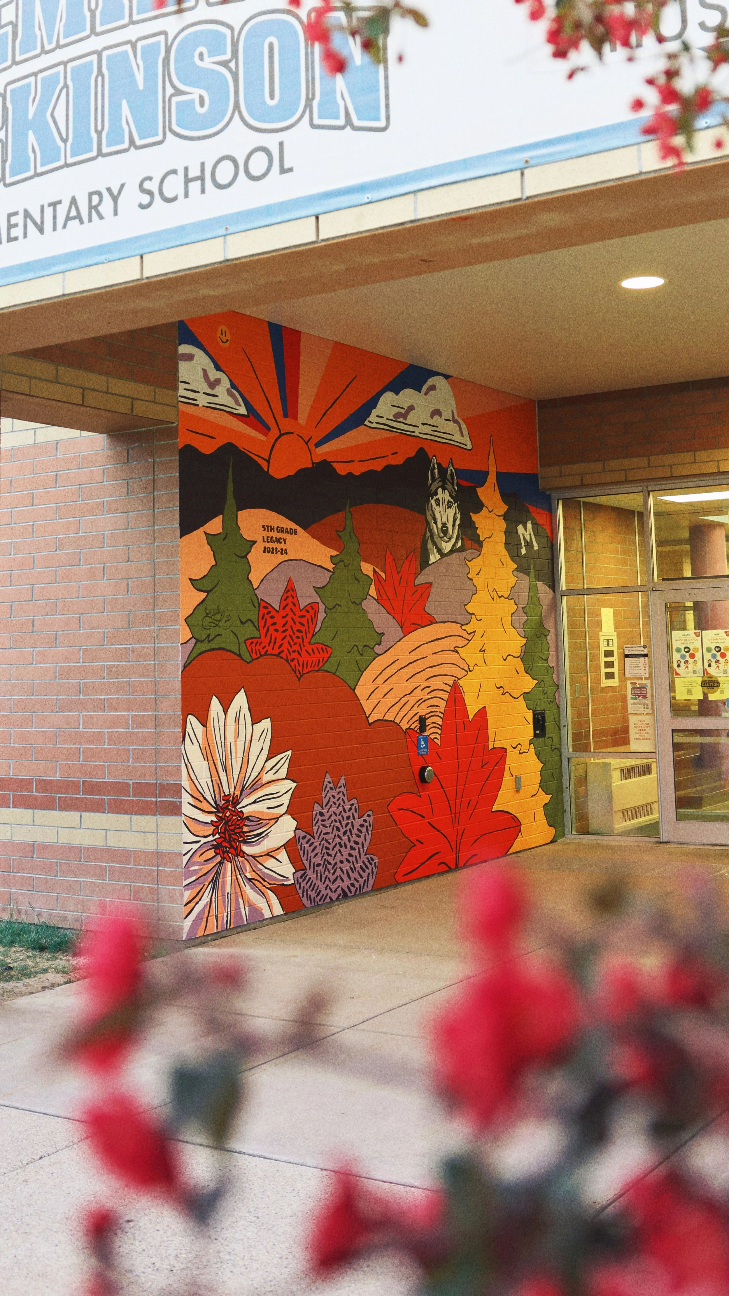 Colorful mural at elementary school featuring a sunset, mountains, trees, a dog, and autumn leaves.