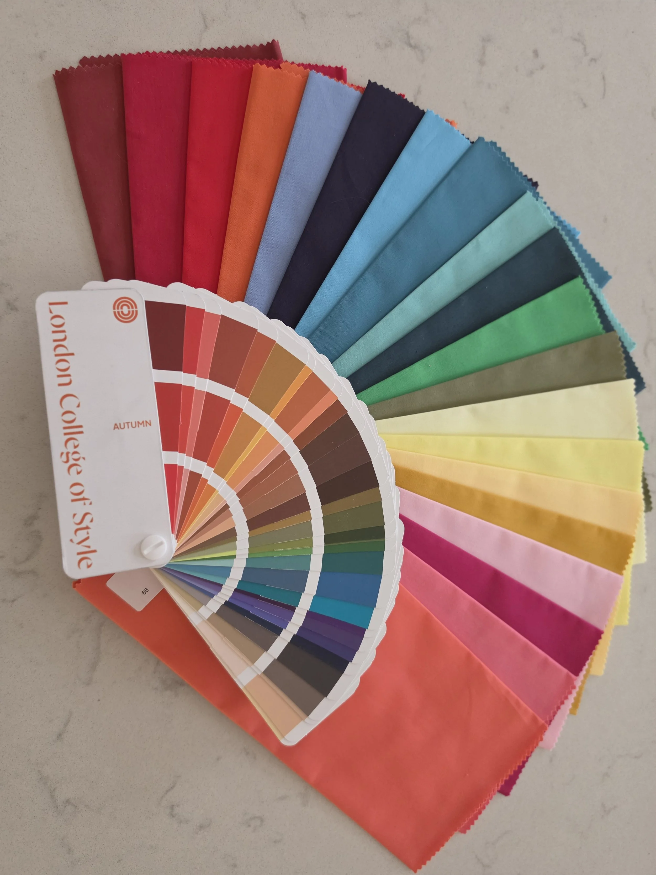 Color swatch fan deck with various shades of pastel and vibrant colors, laid out on a white surface.