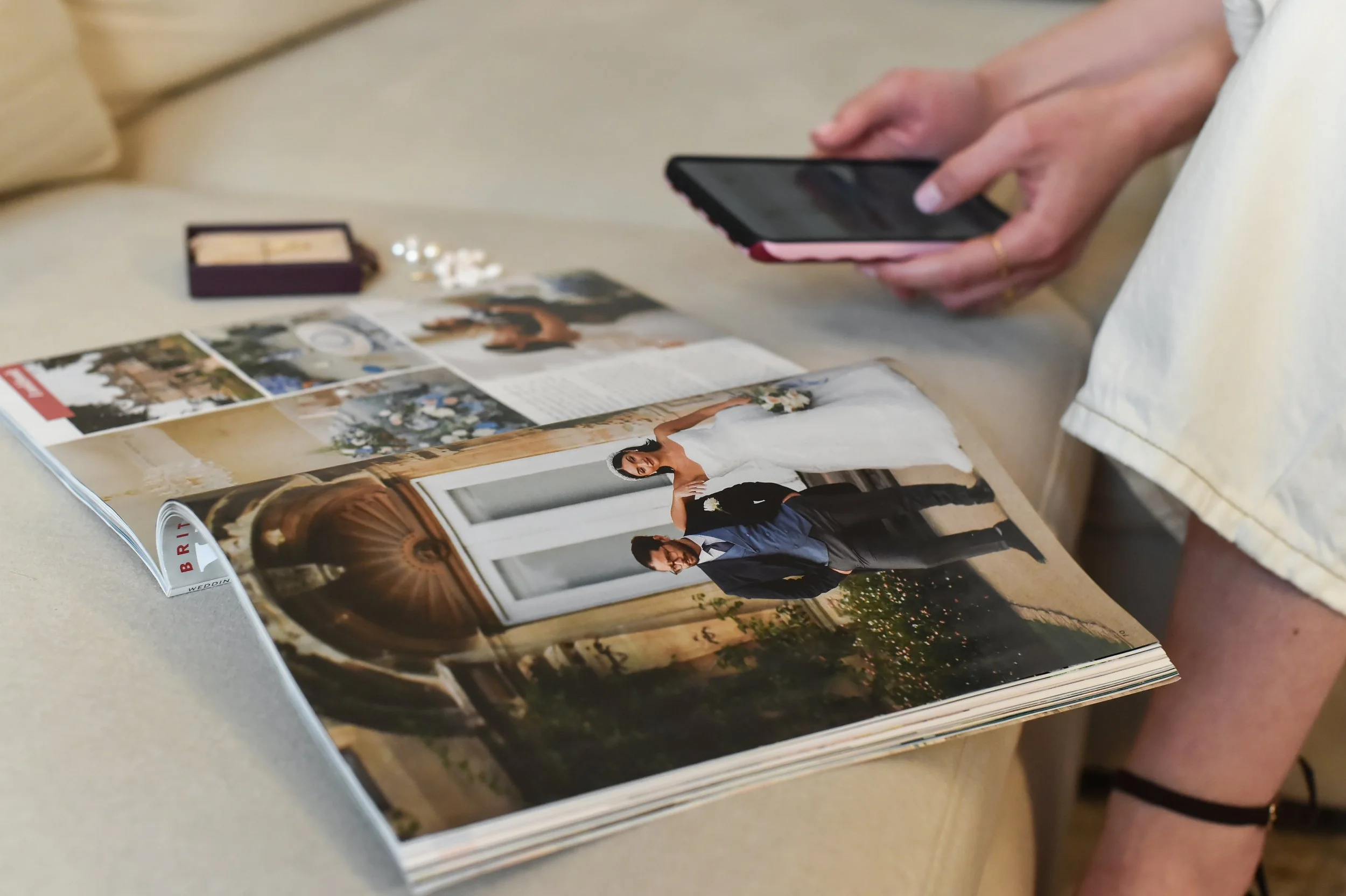 A magazine open to a wedding spread featuring a bride and groom in wedding attire, with wedding decor and photos seen in the background.