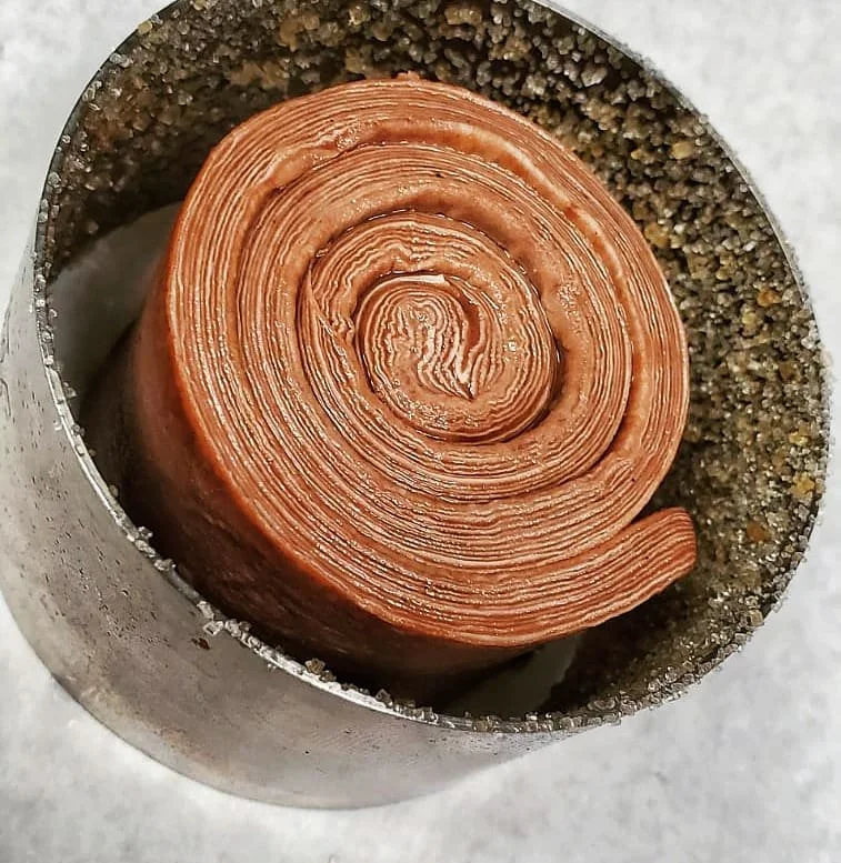 Close-up of a cinnamon roll with a spiral shape, inside a metal baking tube with a sweet sugar coating fresh from our myrtle beach bakery