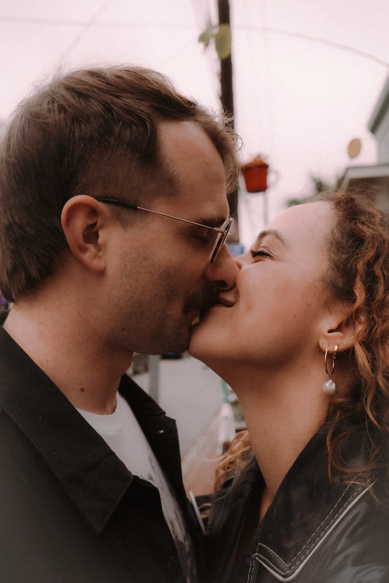 A young man and woman are close, about to kiss, with noses touching and eyes closed.