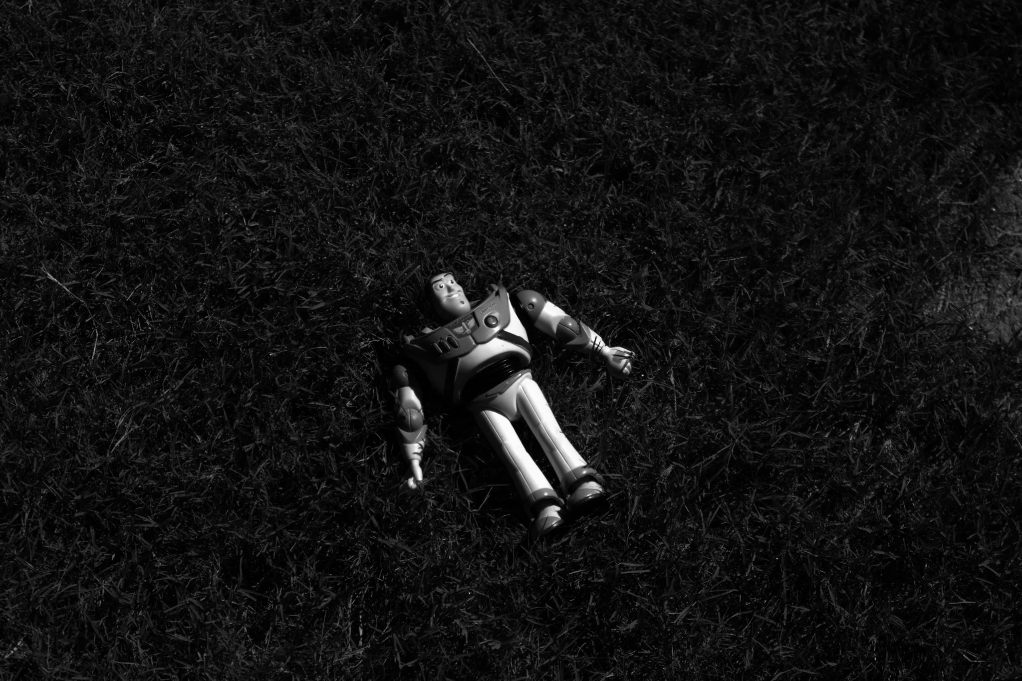 Toy Buzz Lightyear lying on grass in black and white