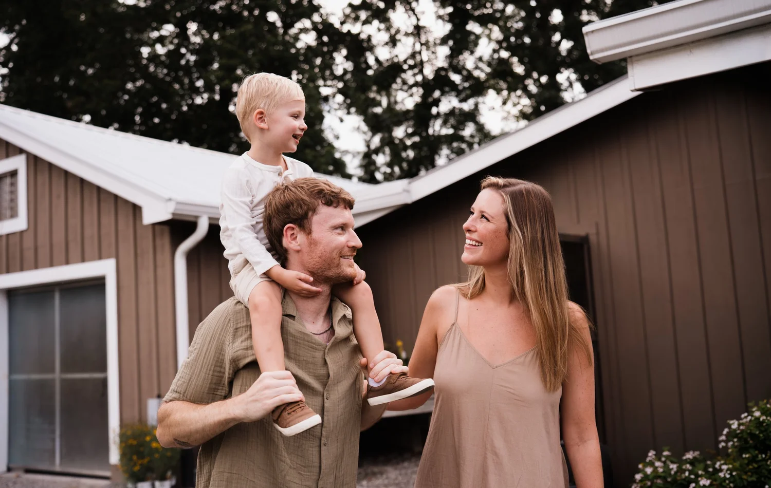Parents smiling with their toddler riding on dad’s shoulders