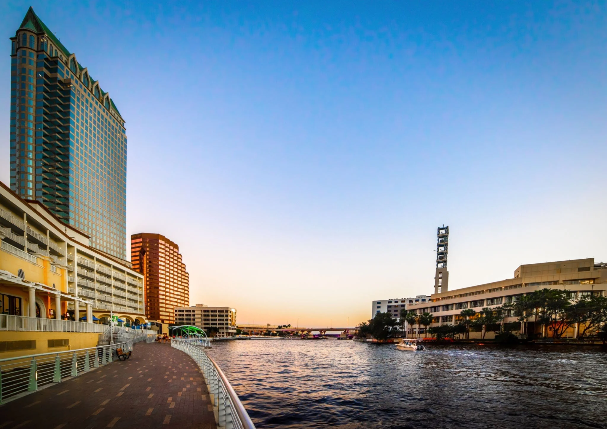 Downtown Tampa Riverwalk skyline illuminated along the Hillsborough River at sunset
