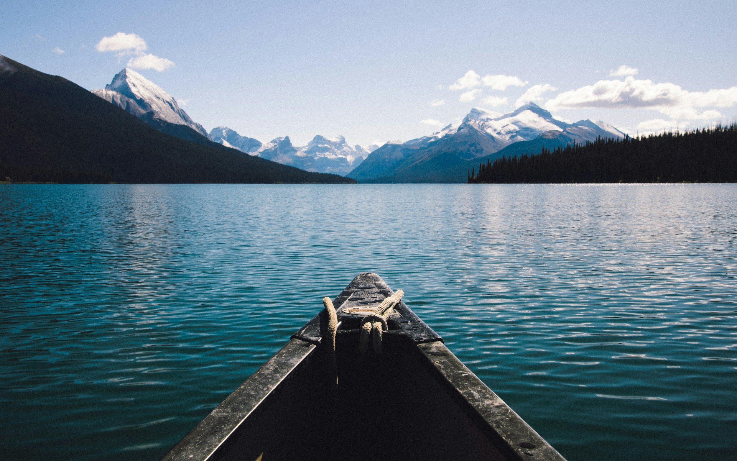 Canoe floating on calm water with mountains in the background at Calming Tides Therapy