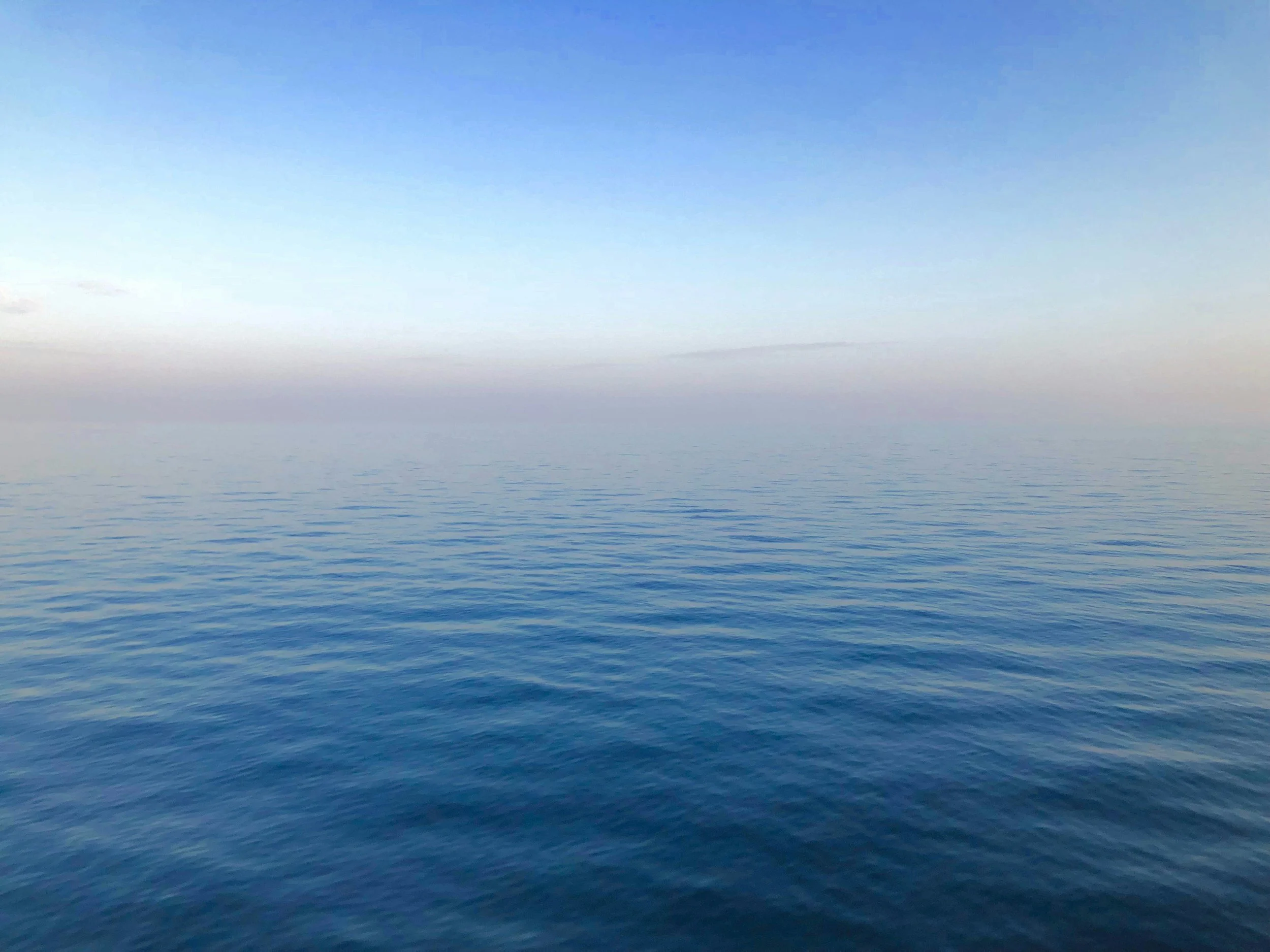 Gentle ocean waves touching a calm sandy shore at sunrise at Calming Tides Therapy