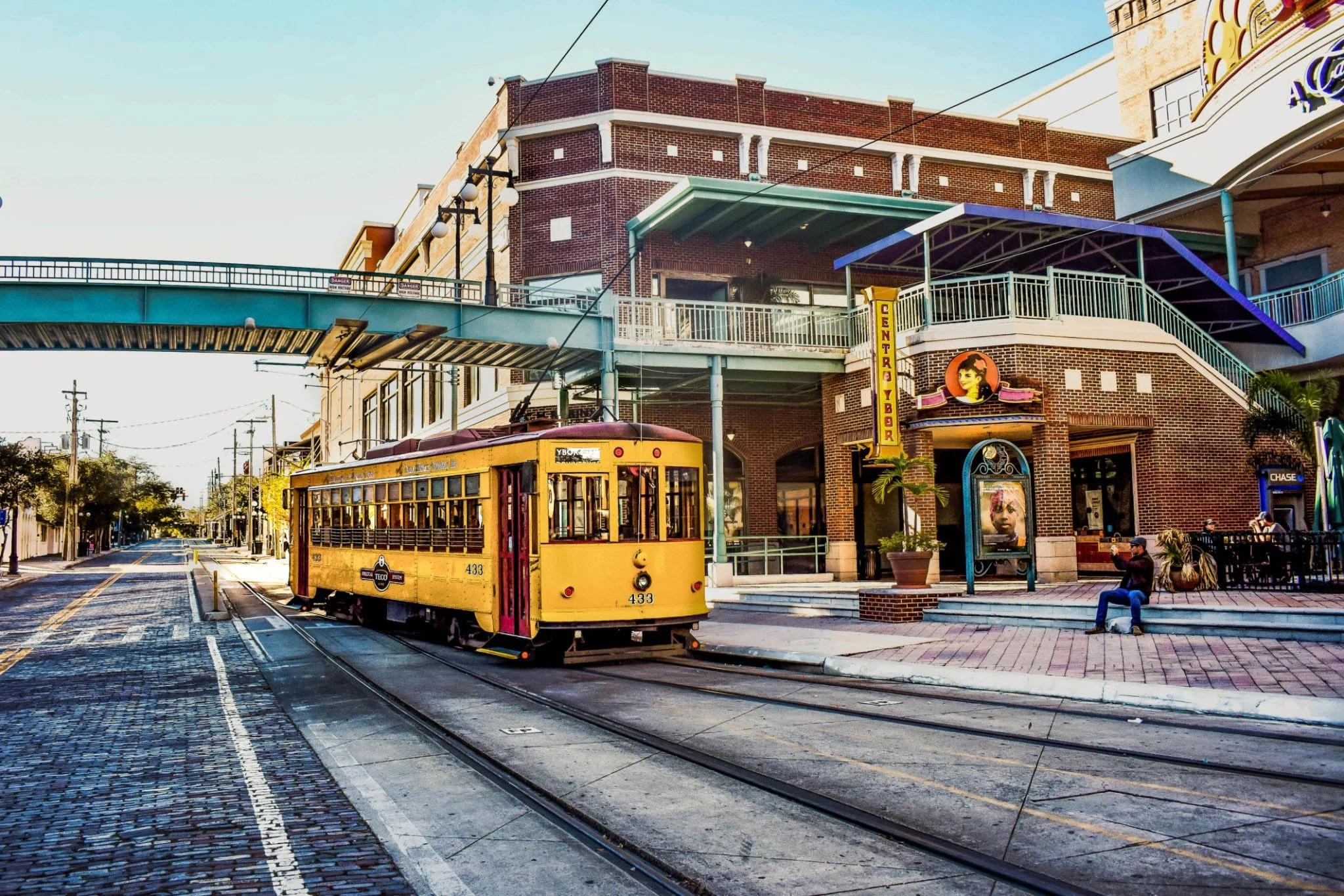 Yellow historic TECO Line Streetcar traveling down brick streets in Ybor City Tampa