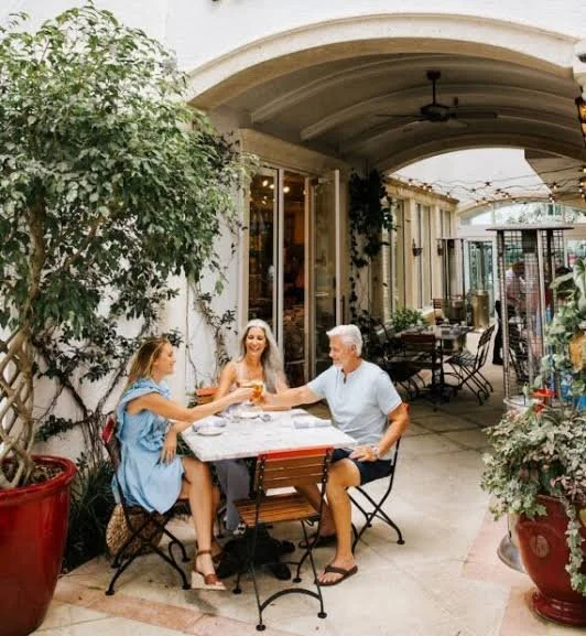 Group of adults conversing together at an elegant sunlit terrace table in Olde Naples, Florida